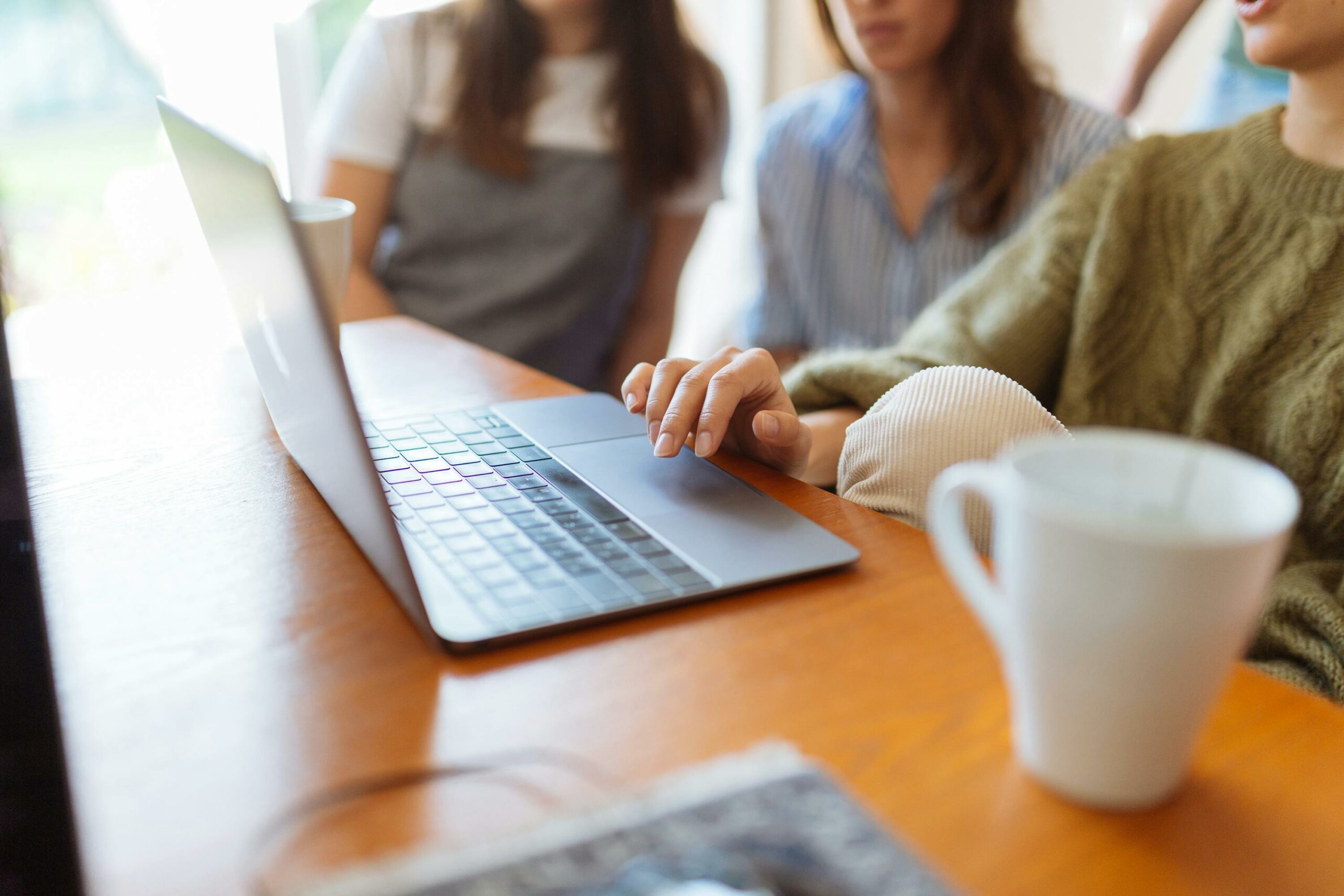 Three people sat around a desk opening a laptop