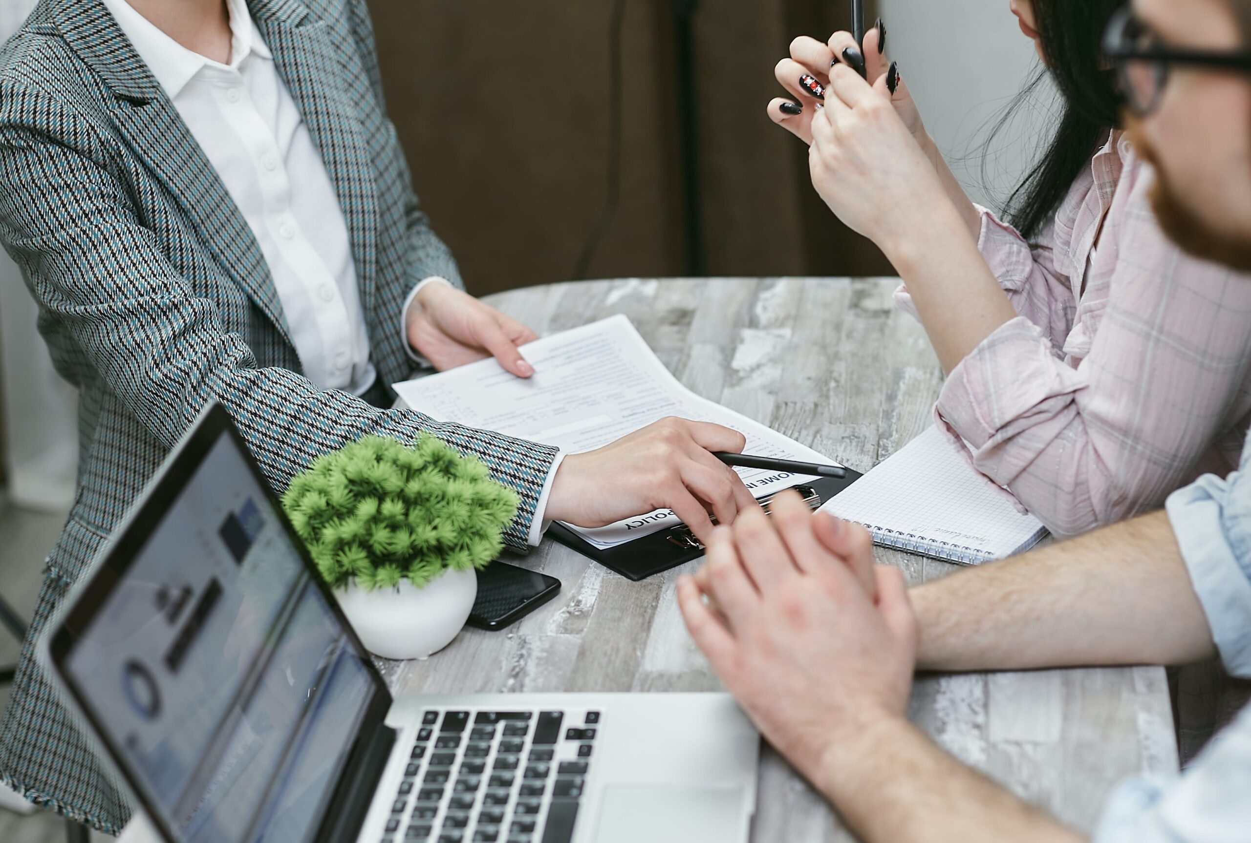 a group of people sat around a desk. One has a clipboard with a checklist of compliant